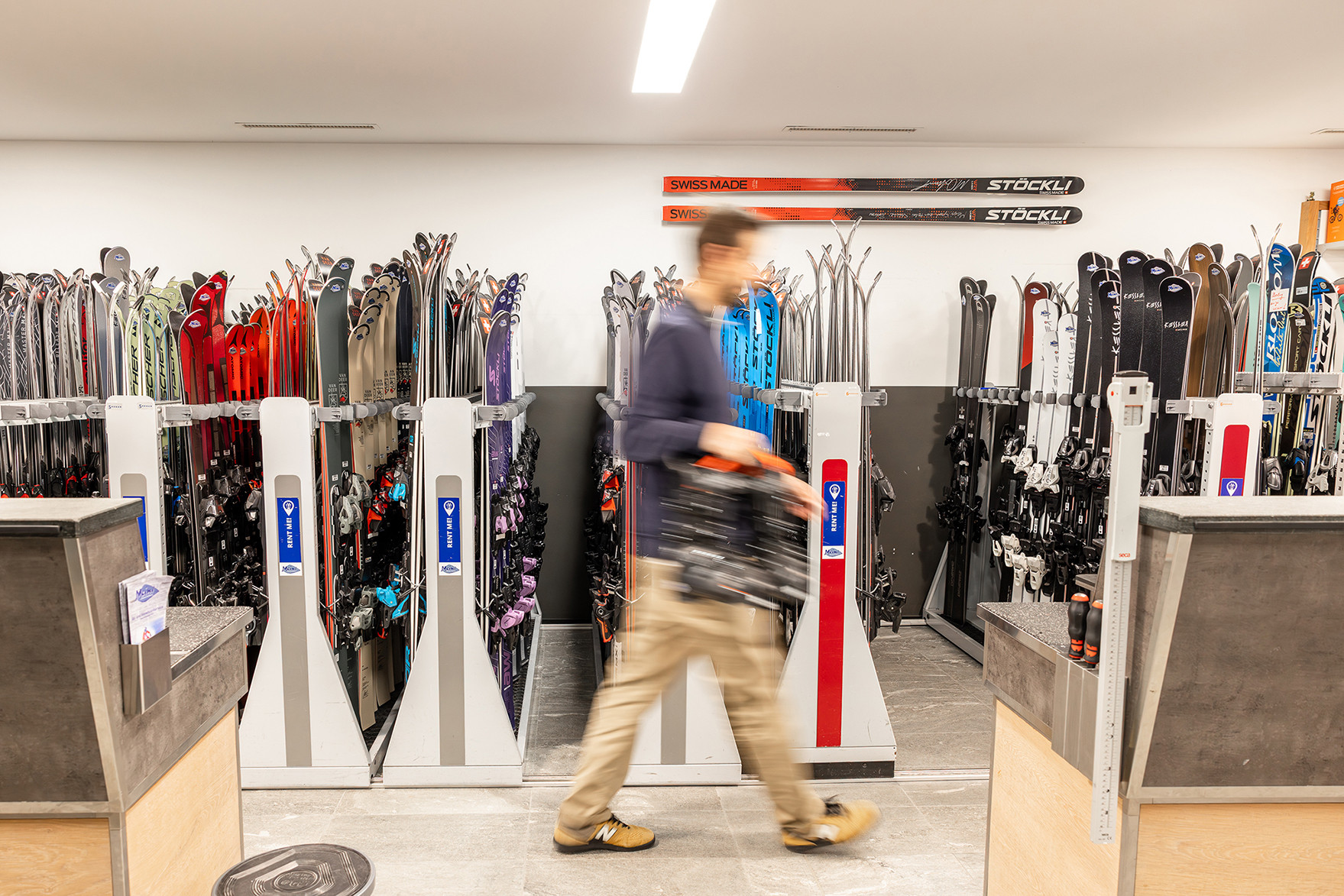 Viele Ski in Skiständern mit verschwommener Person im Vordergrund