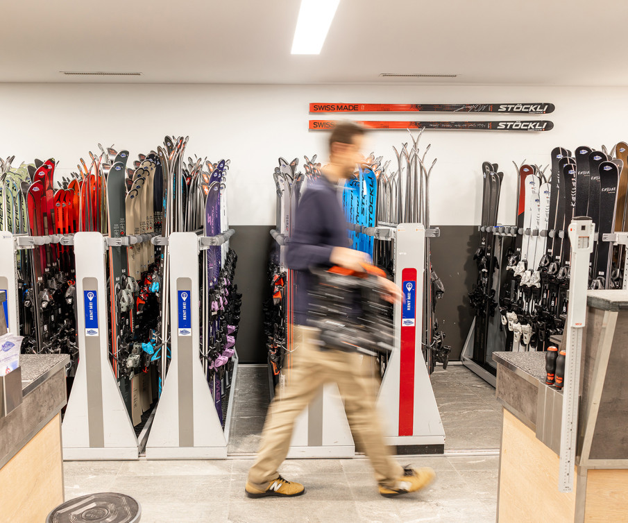 Viele Ski in Skiständern mit verschwommener Person im Vordergrund